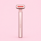 A handheld beauty device with a metallic rose gold handle and a head featuring a row of red LED light dots, shown against a solid light pink background.
